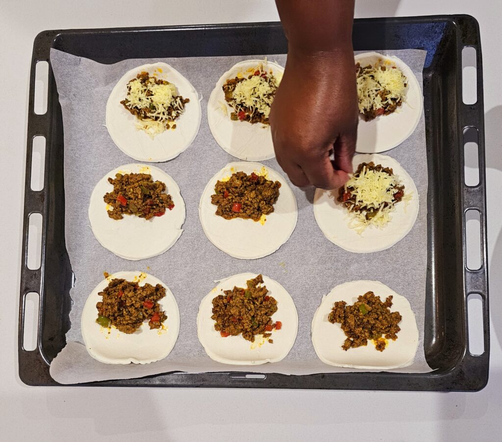 Place 1-2 tablespoons of the beef filling in the center of each dough circle. Sprinkle a generous amount of shredded cheese over the beef.