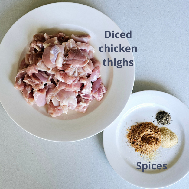chicken thighs diced in a white plate and spices 